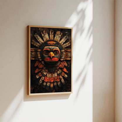 A framed art print featuring a detailed, stylized totem-style bird or sun face in dark brown, black, red, and beige tones, hanging on a warm off-white wall with soft diagonal shadows.