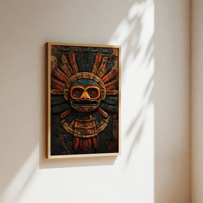 A framed wall art print featuring an Aztec-style calendar mask with a dark wood background and warm orange, brown, and red details, hung on a beige wall with soft sunlight and leaf shadows.
