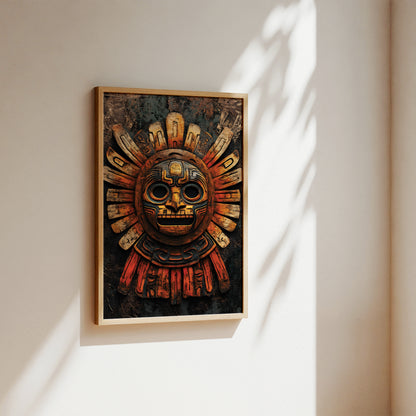 A framed art print featuring an Aztec-style sun mask with gold, red, and black details, hanging on a warm beige wall with soft sunlight and leaf shadows.