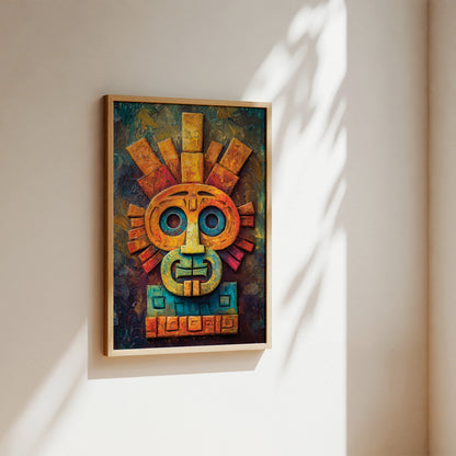 A framed colorful wall art piece featuring an abstract Aztec-style face with geometric details, hanging on a beige wall with soft sunlight and leaf shadows.