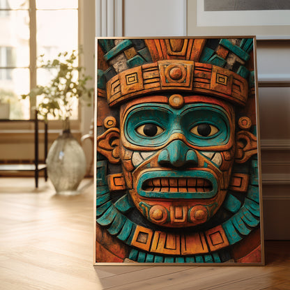 A framed art print featuring a detailed Aztec-style mask with turquoise and orange-brown tones, leaning against a wall on a light wood floor in a softly lit room.