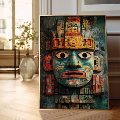 A framed art print featuring a detailed Aztec-style face mask with turquoise, gold, red, and black tones, leaning against a wall on a light wood floor in a modern room setting.