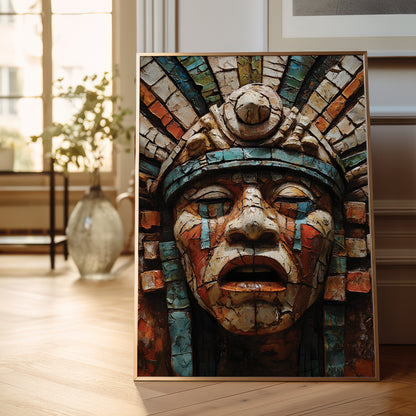 A framed art print featuring a highly detailed, textured Aztec-style face with a feathered headdress, displayed leaning against a wall on a light wood floor in a bright, modern room.