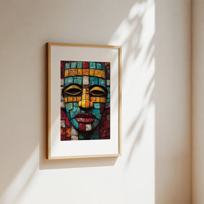 A framed art print featuring a colorful mosaic face, hung on a warm beige wall with soft sunlight and leaf shadows casting across it.