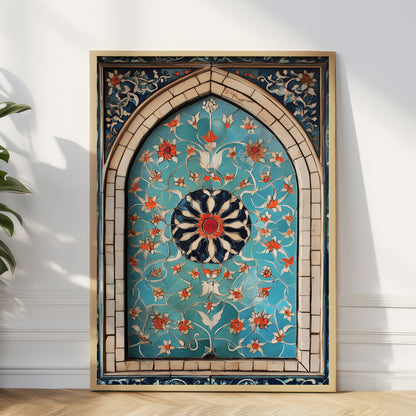 A large framed Islamic wall art piece featuring an intricate turquoise, gold, and orange floral pattern inside an arched frame, leaning against a white wall on a light wood floor.
