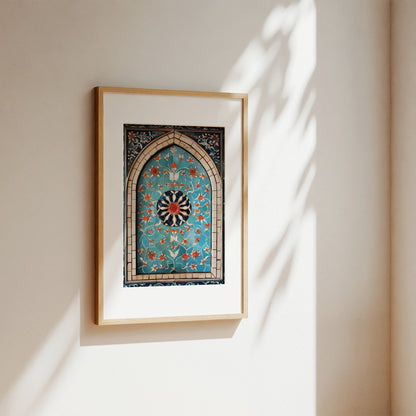A framed art print featuring an intricate turquoise and gold Islamic geometric arch pattern, mounted on a warm beige wall with soft sunlight and leaf shadows casting across it.
