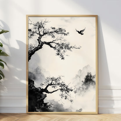 A framed vertical art print featuring a black ink-style landscape with tree branches, misty mountains, and a flying bird, displayed against a white wall on a light wood floor.