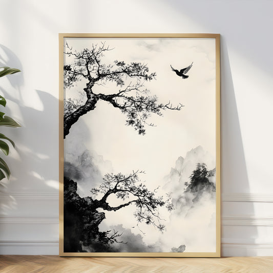 A framed vertical art print featuring a black ink-style landscape with tree branches, misty mountains, and a flying bird, displayed against a white wall on a light wood floor.