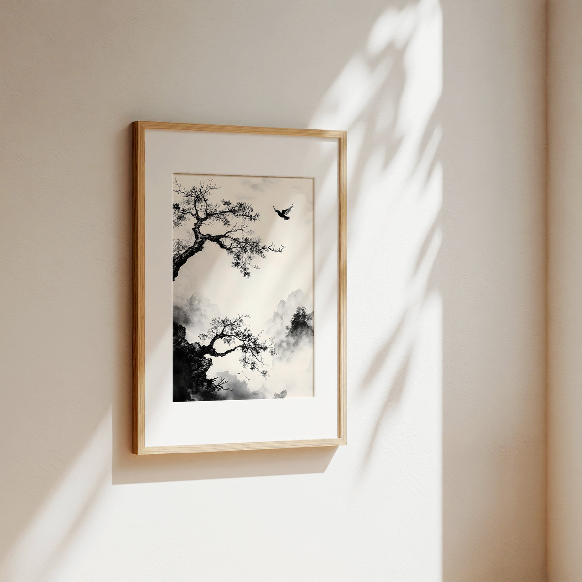 A framed black and white ink-style art print of a tree and bird, displayed on a warm beige wall with soft sunlight and leaf shadows.