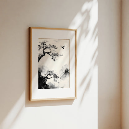 A framed black and white ink-style art print of a tree and bird, displayed on a warm beige wall with soft sunlight and leaf shadows.