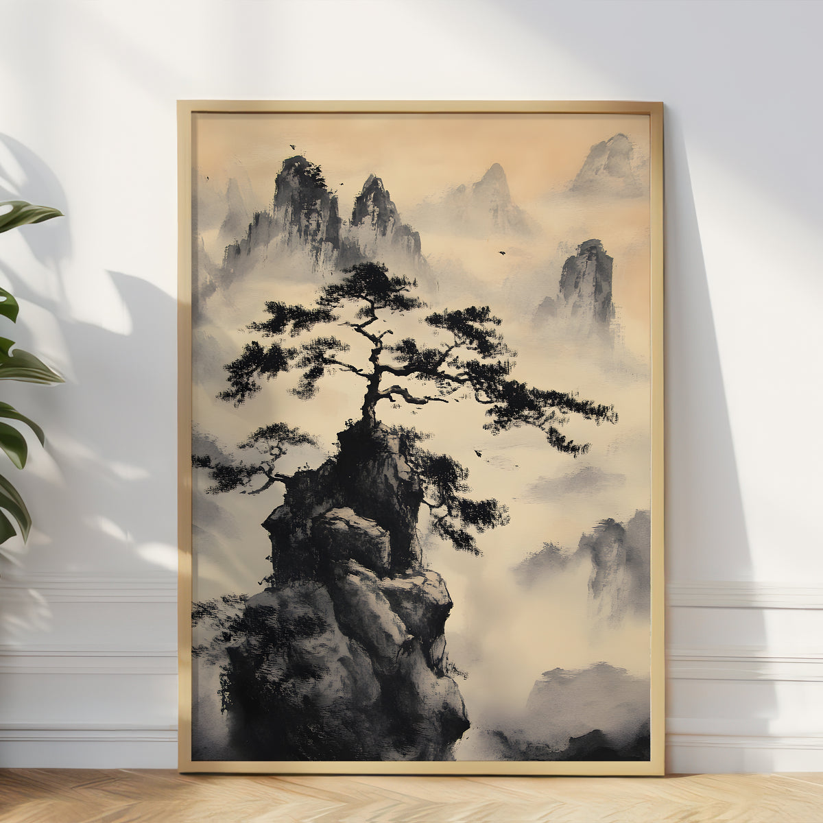 A framed vertical art print featuring a black ink-style pine tree on a rocky outcrop with misty mountains in the background, leaning against a white wall on a light wood floor.