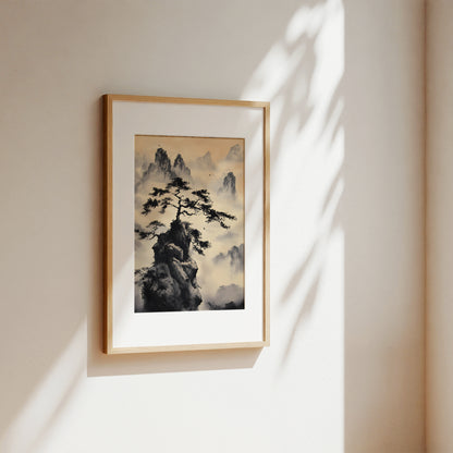 A framed art print featuring a traditional Chinese ink painting of a pine tree on a rocky cliff surrounded by misty mountains, displayed on a warm beige wall with soft sunlight and leaf shadows.