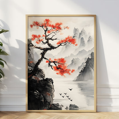 A framed vertical art print depicting a traditional Chinese landscape with a vibrant red tree, misty mountains, water, and birds, leaning against a white wall on a light wood floor.