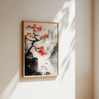 A framed landscape art print featuring a traditional Chinese-style scene with a red-leafed tree, rocky cliffs, misty mountains, and a calm lake, displayed on a warm beige wall with soft sunlight and leaf shadows.