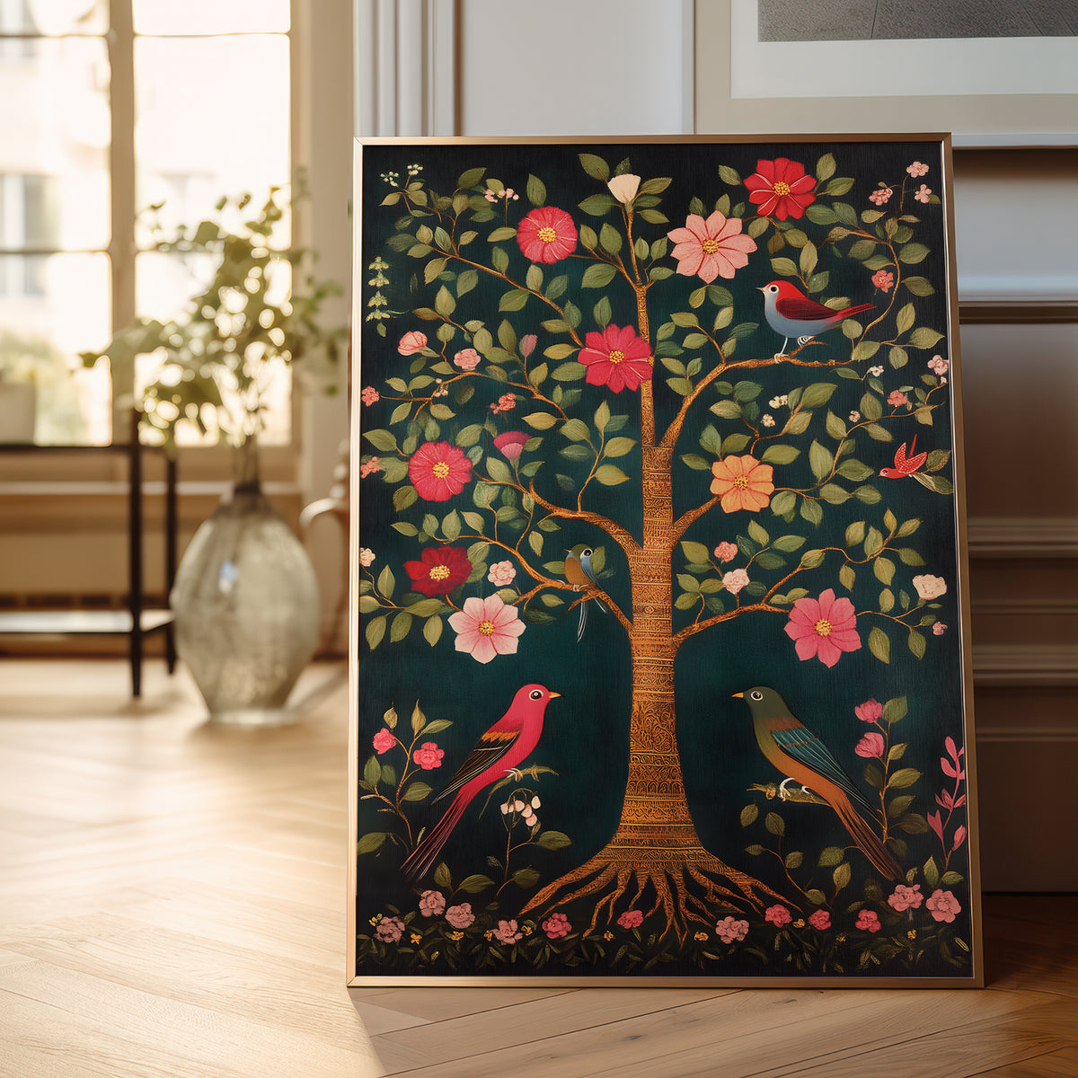 A framed vertical art print depicting a stylized tree of life with pink and red flowers, green leaves, and colorful birds on a dark teal background, leaning against a light-colored wall on a wooden floor.