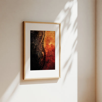 Framed abstract wall art hanging on a beige wall, with warm orange, red, and black artwork inside a light wood frame and a white mat. Sunlight casts leaf-like shadows across the wall.