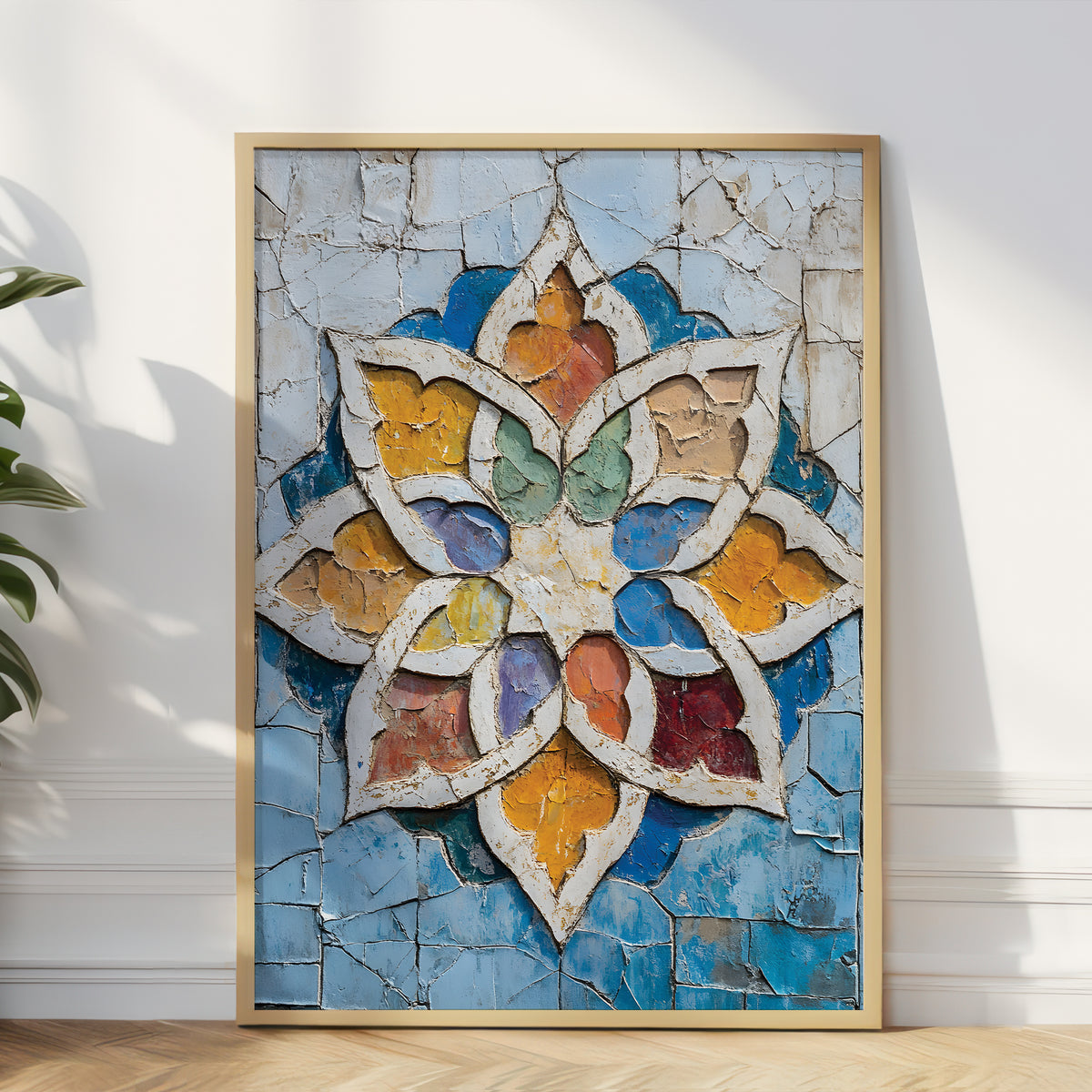 A framed square art print leaning against a white wall on a light wood floor, featuring a colorful cracked-glass style floral or mandala design with blue, gold, white, green, and red tones.