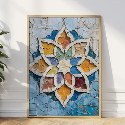 A framed square art print leaning against a white wall on a light wood floor, featuring a colorful cracked-glass style floral or mandala design with blue, gold, white, green, and red tones.