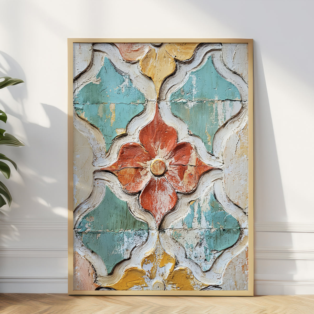 A framed wall art print leaning against a white wall on a light wood floor, showing a distressed geometric floral pattern in turquoise, cream, mustard yellow, and terracotta tones.