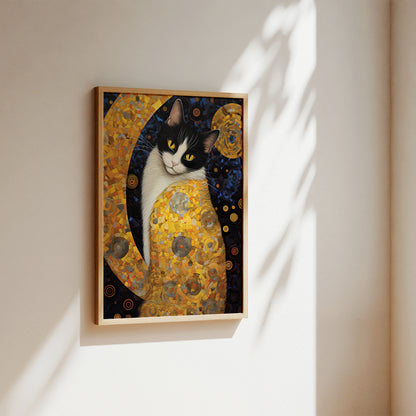 A framed art print of a black and white cat painted in a Gustav Klimt style with gold, yellow, and dark blue tones, hanging on a beige wall with soft sunlight and leaf shadows.