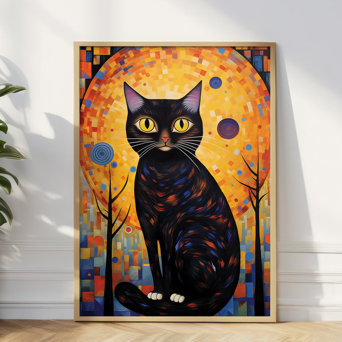 A framed vertical art print featuring a stylized black cat with glowing yellow eyes in front of a large orange circular backdrop, leaning against a white wall on a wood floor with a plant partially visible at the left edge.