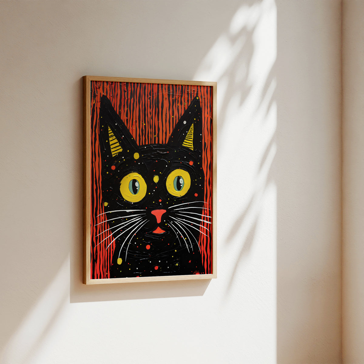 A framed art print of a stylized black cat with large yellow eyes and red vertical stripes, hanging on a beige wall with soft sunlight and leaf shadows.