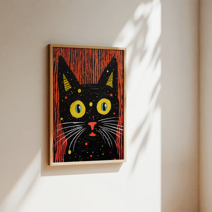 A framed art print of a stylized black cat with large yellow eyes and red vertical stripes, hanging on a beige wall with soft sunlight and leaf shadows.