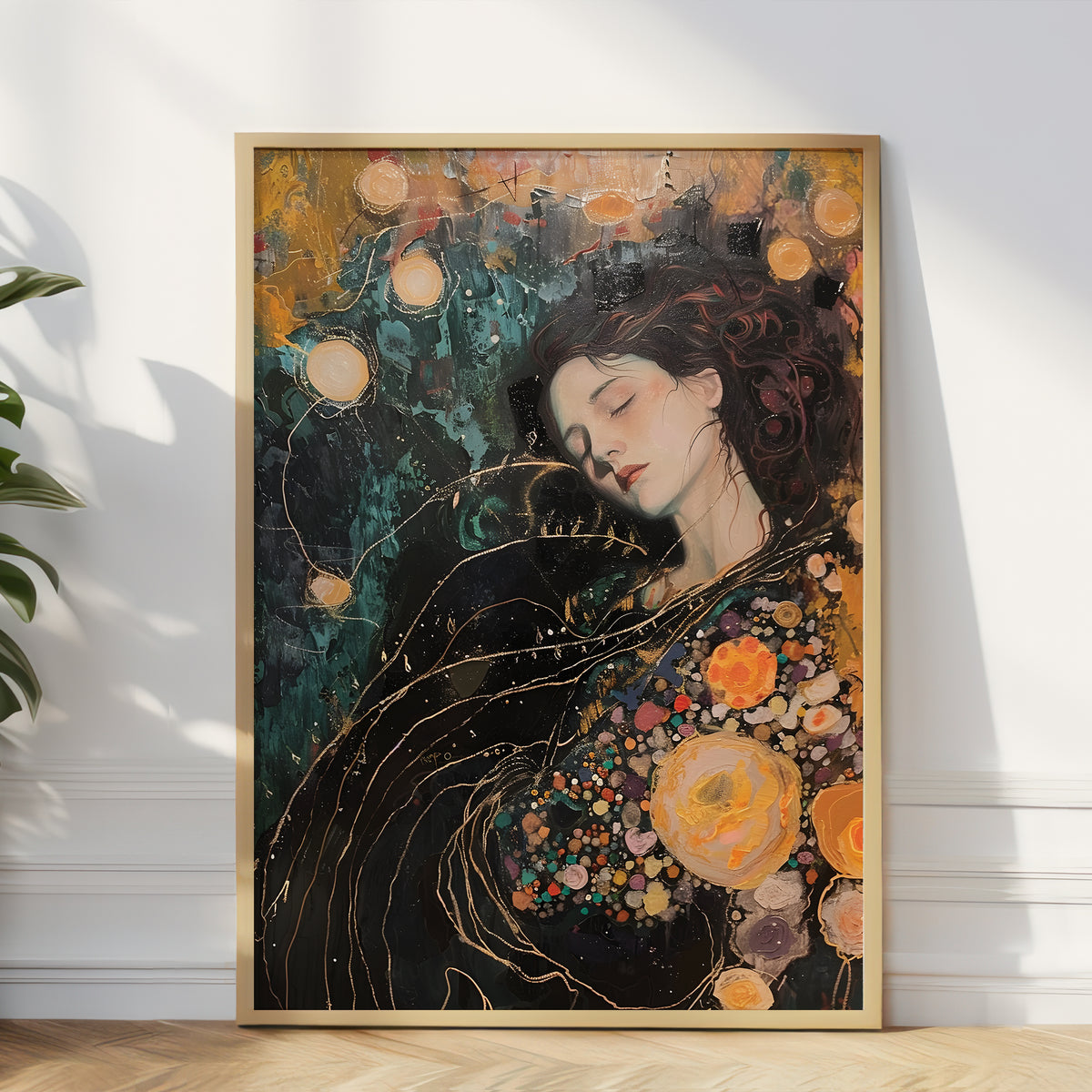 A framed vertical art print leaning against a white wall on a light wood floor, showing a stylized portrait of a woman with closed eyes surrounded by abstract floral and glowing circular motifs in dark teal, black, gold, and orange tones.
