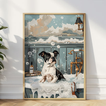 A framed art print leaning against a white wall on a light wood floor. The print shows a black and white dog sitting in a bubble-filled bathtub with a vintage brass faucet, a bottle, and a seascape in the background.