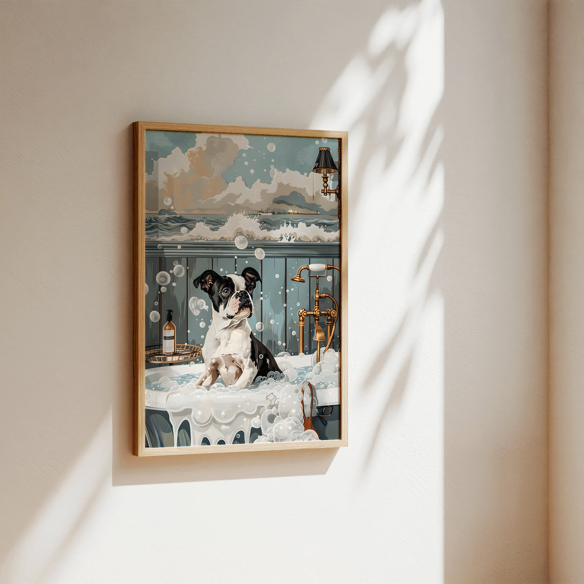 A framed art print depicting a black and white dog sitting in a luxurious steaming bathroom with bubbles, gold fixtures, and a blue-gray background, displayed on a warm beige wall with soft sunlight and leaf shadows.