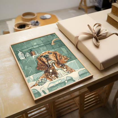 A framed art print depicting a wet dog in a bathtub scene, styled on a wooden table next to a wrapped gift box with a beige ribbon.