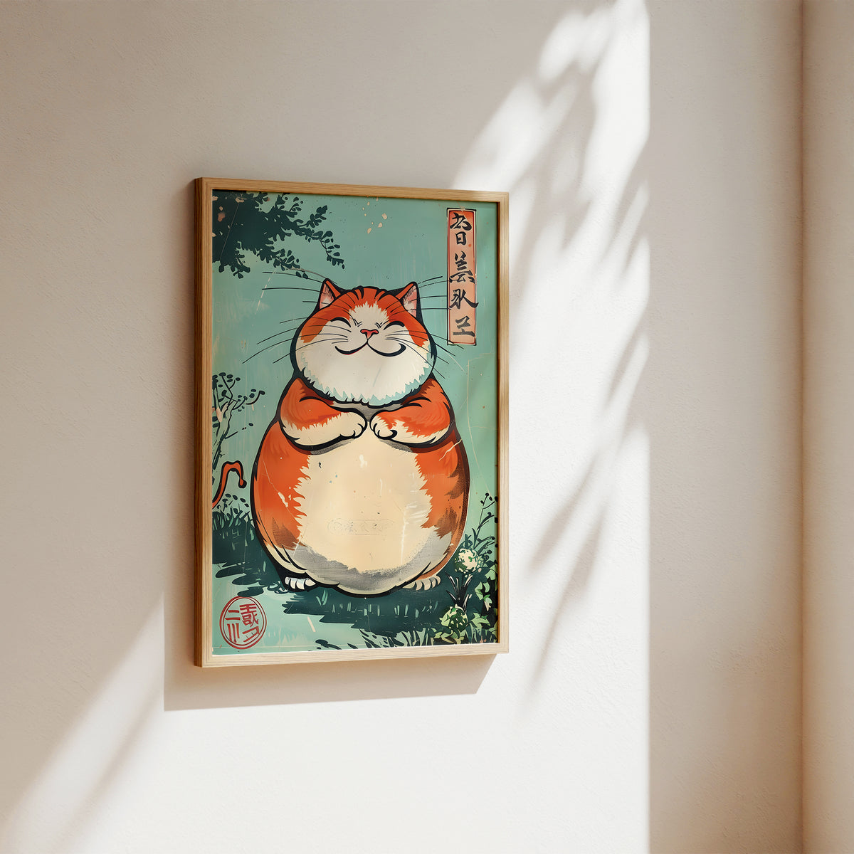 A framed art print featuring a cute, chubby orange and white cat in a Japanese ukiyo-e style, hanging on a warm beige wall with soft sunlight and leaf shadows.