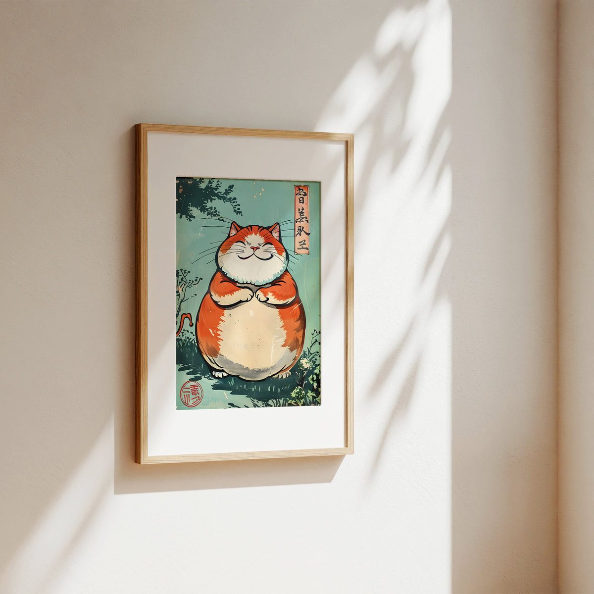 A framed art print featuring a cute, chubby orange and white cat in a Japanese ukiyo-e style, hanging on a warm beige wall with soft sunlight and leaf shadows.
