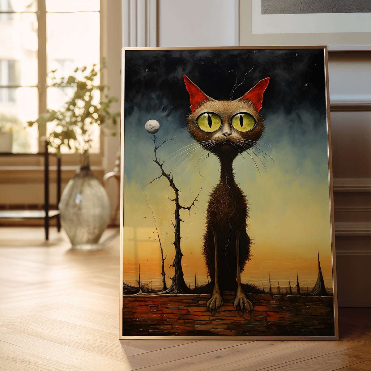 A framed surreal art print depicting a tall brown cat with large green eyes and red ears, standing in a dreamlike landscape at sunset, displayed leaning against a wall in a bright room.