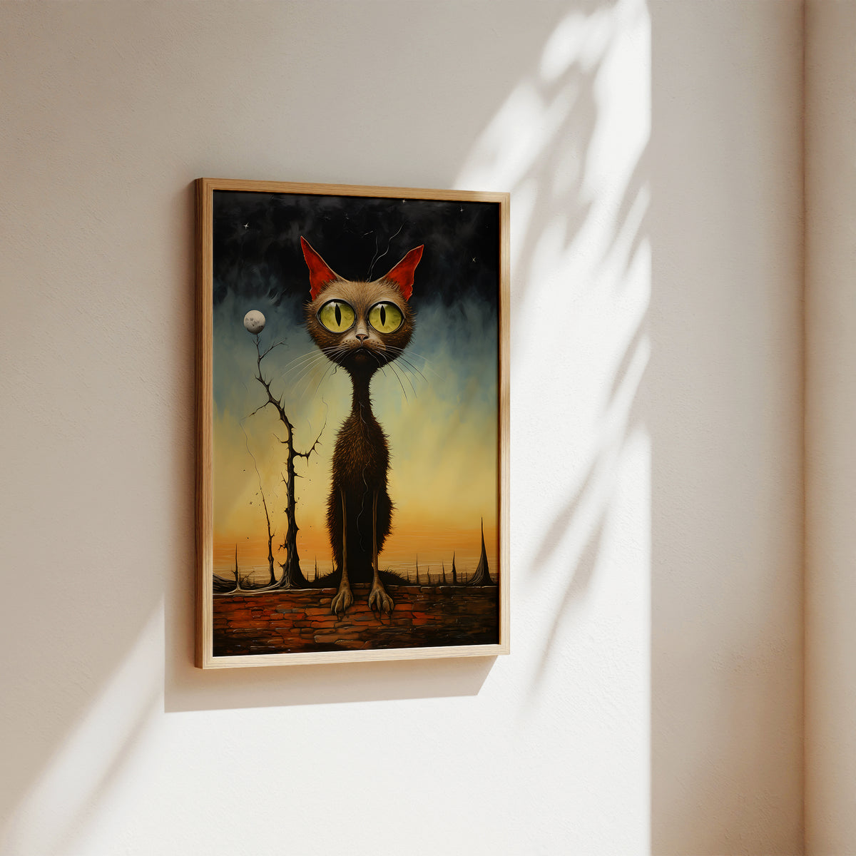 A framed surreal art print of a tall black cat with large yellow eyes and red ears, hanging on a warm off-white wall with soft sunlight and leaf shadows.