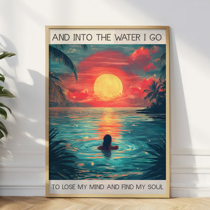 Framed artwork of a person swimming in water with a sunset and palm trees, text 'And into the water I go / To lose my mind and find my soul'.