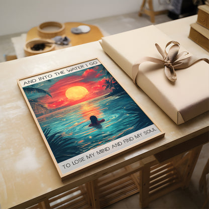 Gift box with a wrapped present and a framed artwork on a wooden table.