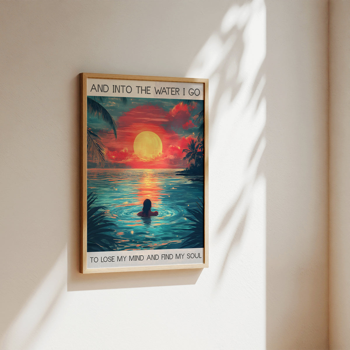 Framed artwork of a sunset over water with a person in the water, text on the wall.