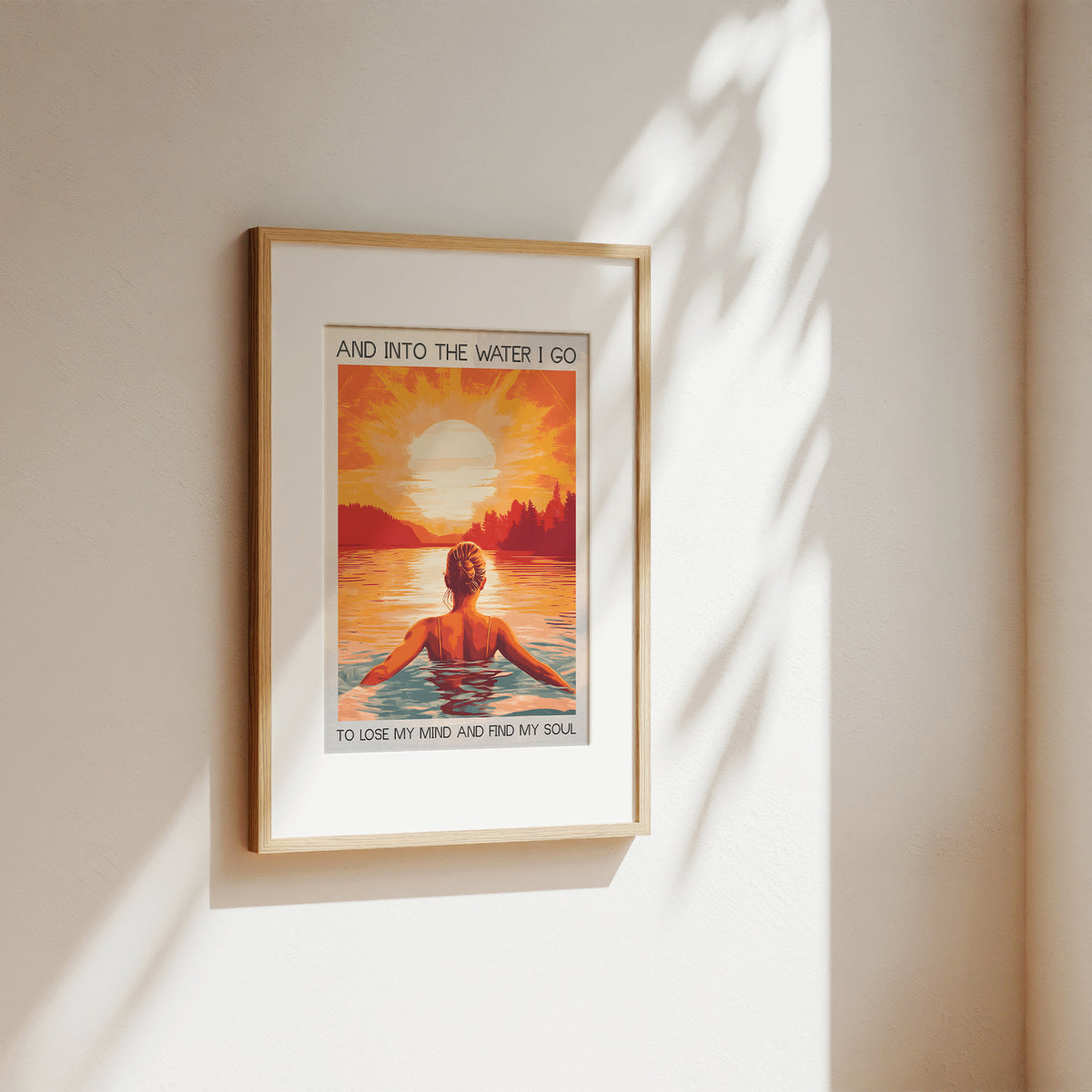 Framed artwork of a person in water with a sunset and text on a beige wall.