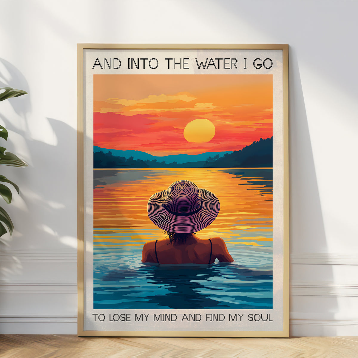 Framed artwork of a person in a hat sitting in water with a sunset over a lake.