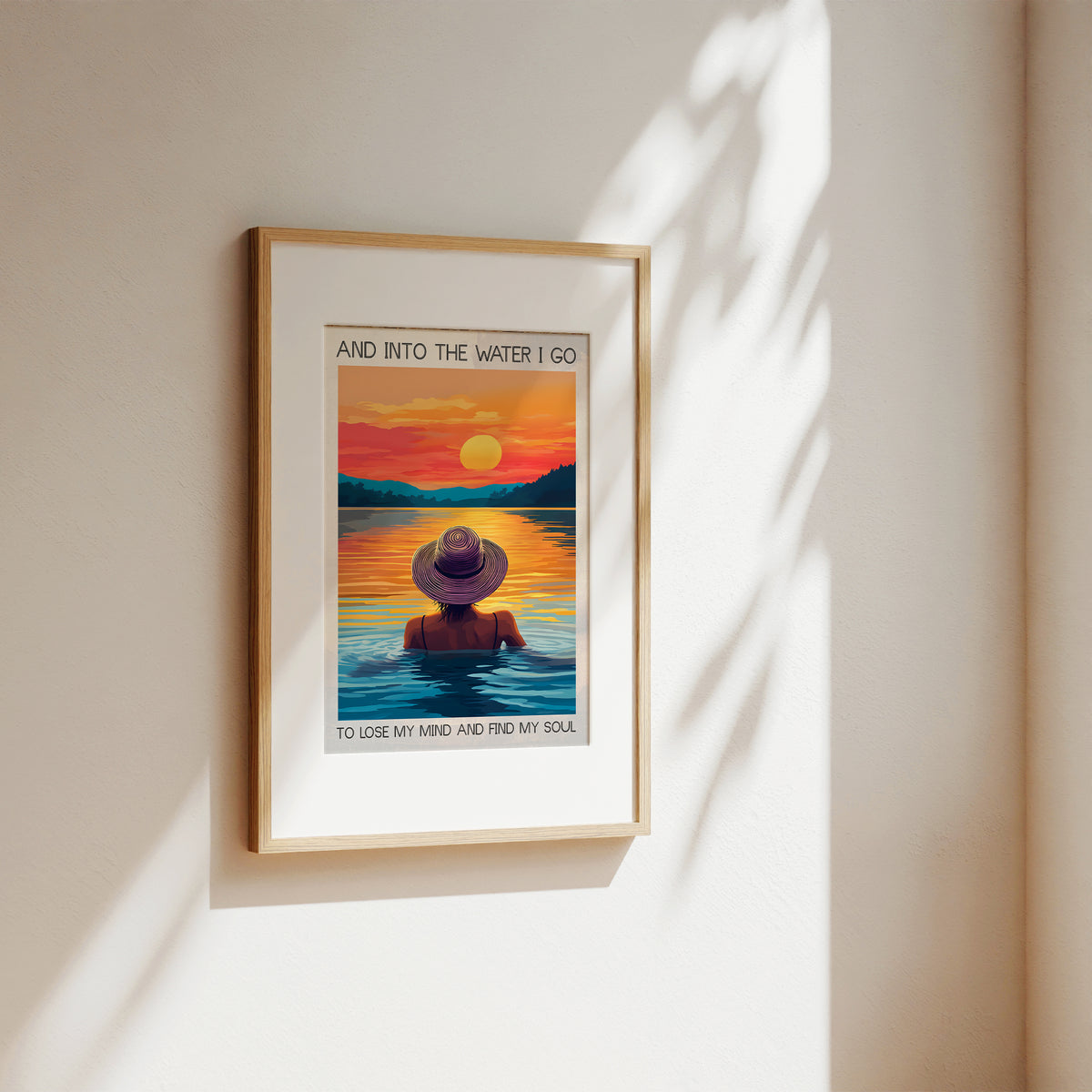 Framed artwork of a person in a hat standing in water with a sunset background, on a beige wall.