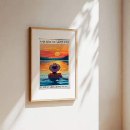 Framed artwork of a person in a hat standing in water with a sunset background, on a beige wall.
