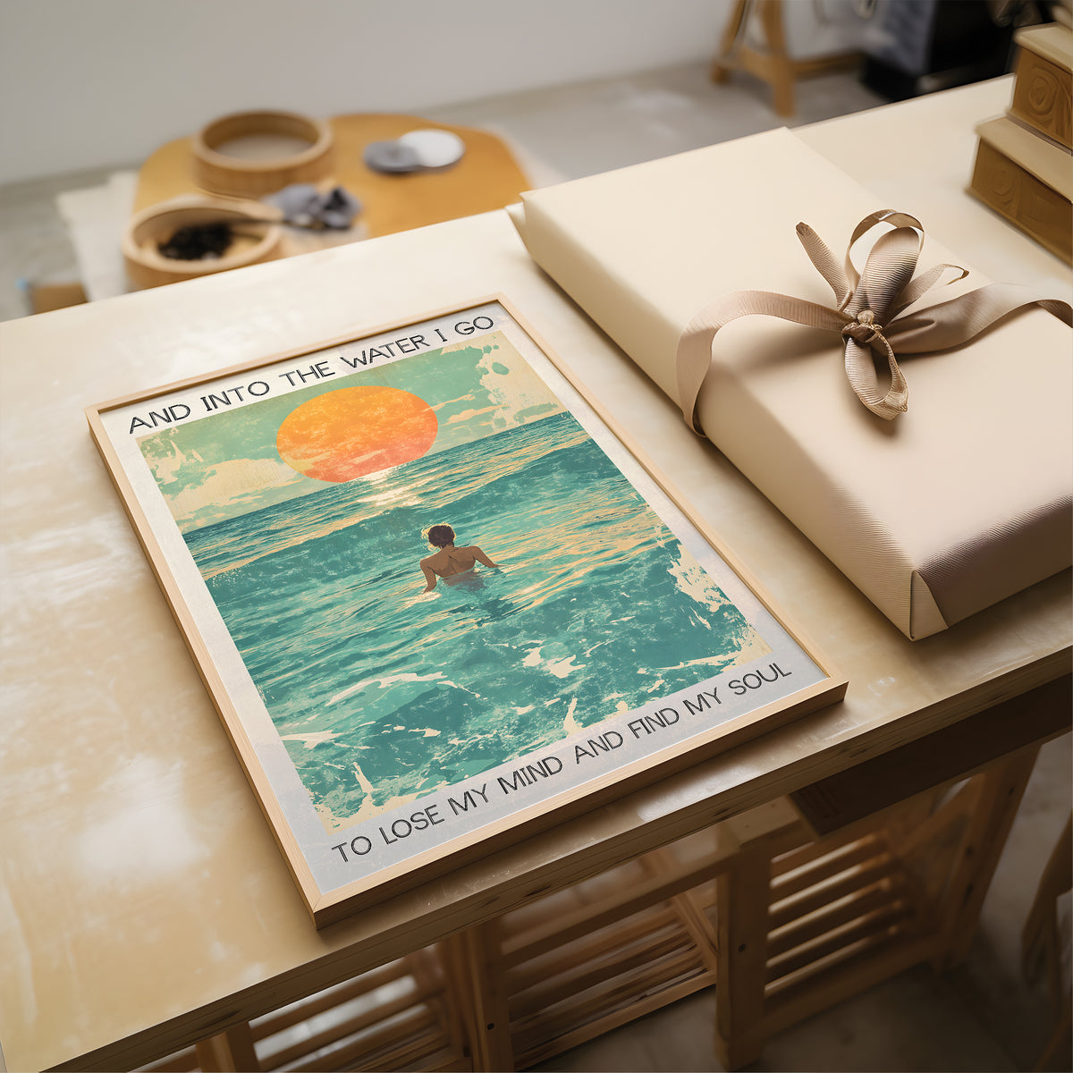 Poster of a person in water with text, placed on a table next to a wrapped gift.