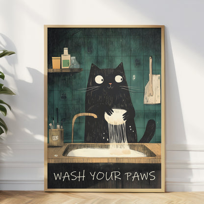 A framed art print featuring a black cat washing its paws in a sink against a dark teal tiled wall, leaning against a white wall on a wooden floor.