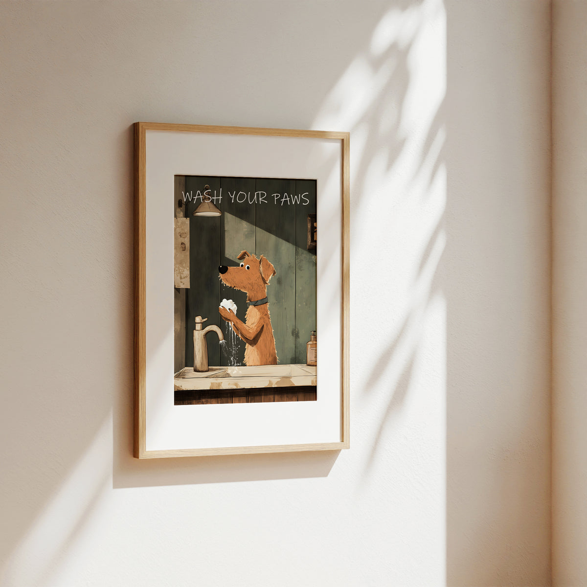 A framed art print featuring an illustration of a dog washing its paws with the text 'WASH YOUR Paws' mounted on a beige wall with soft shadow overlays.