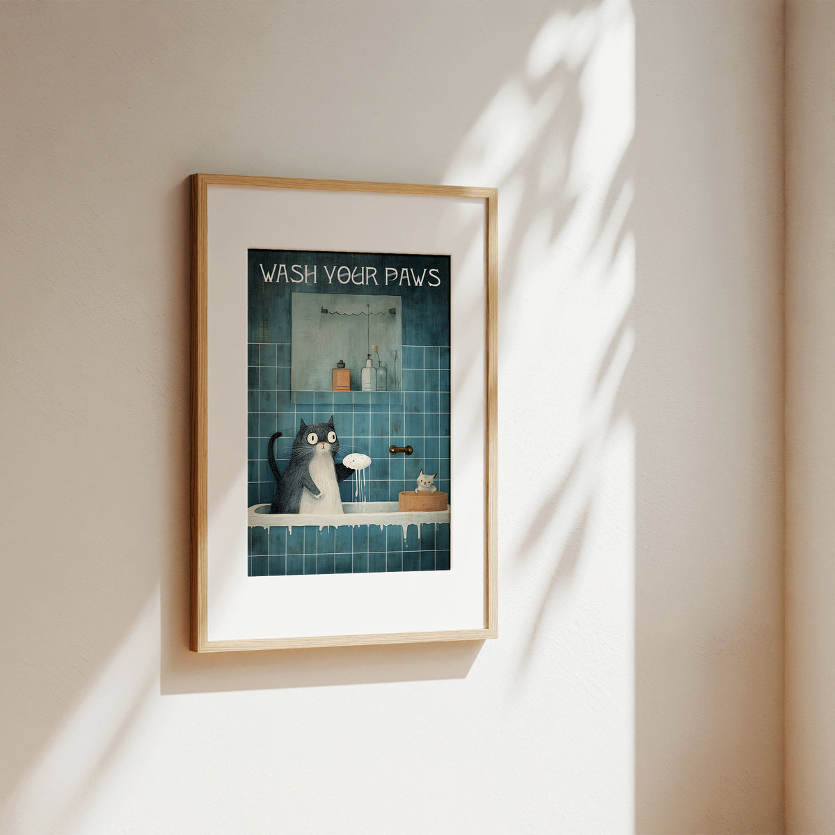 Framed artwork of a cat washing its paws in a bathroom setting on a wall.