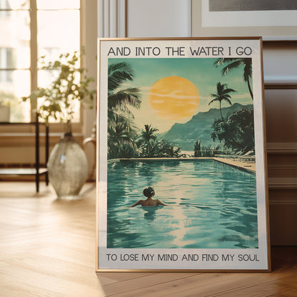 Poster of a person in a pool with palm trees and mountains, placed on a wooden floor.