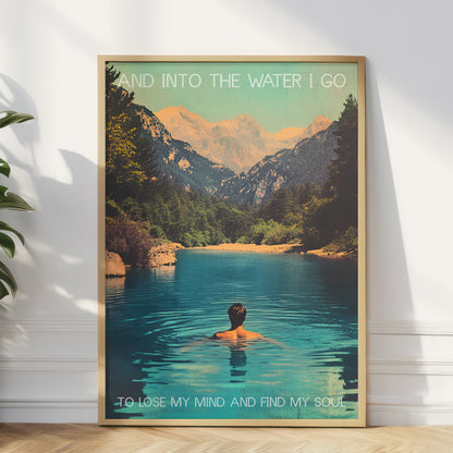 Framed poster of a person in a lake with mountains and text on a white wall.