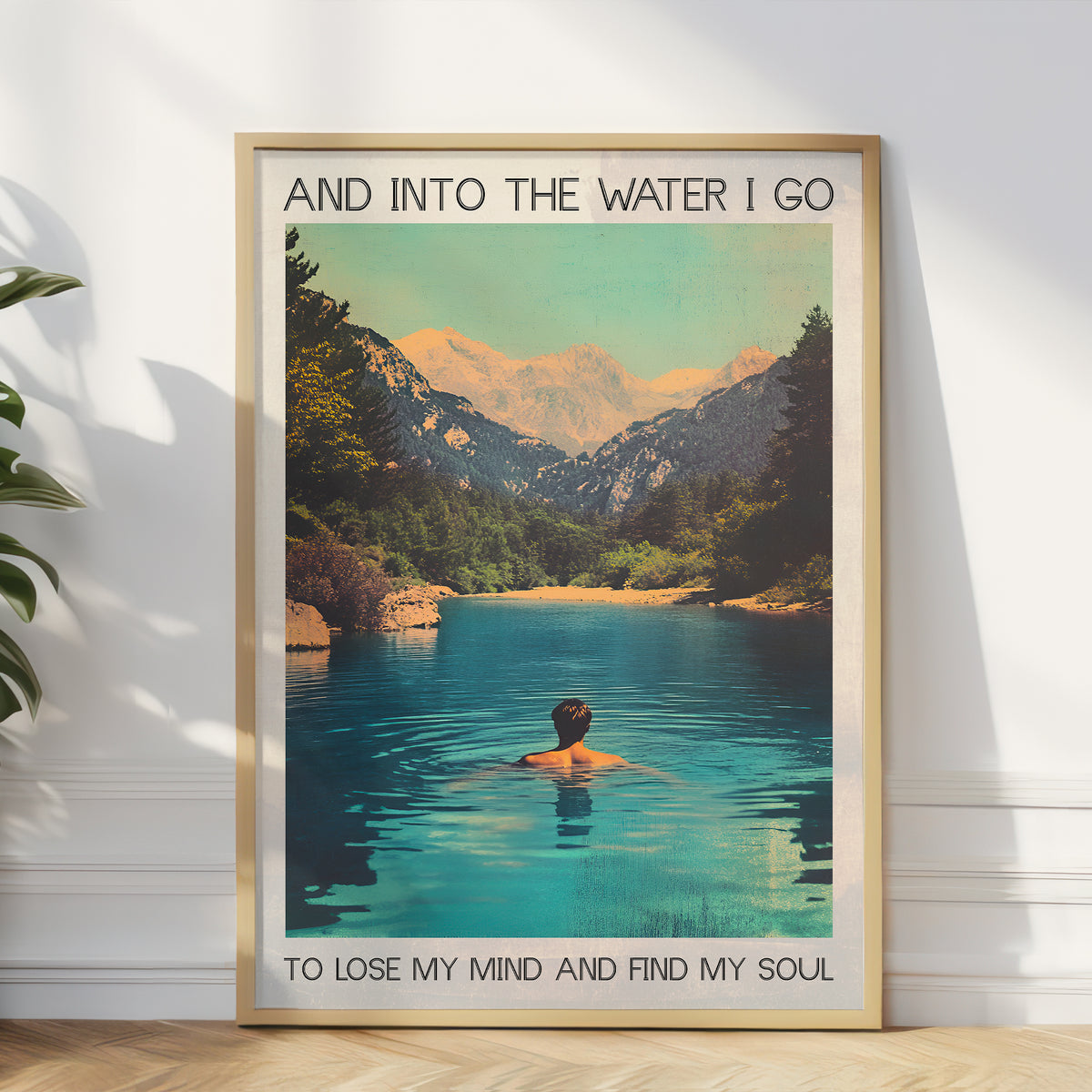 Framed poster of a person swimming in a mountain lake with text on a white wall.