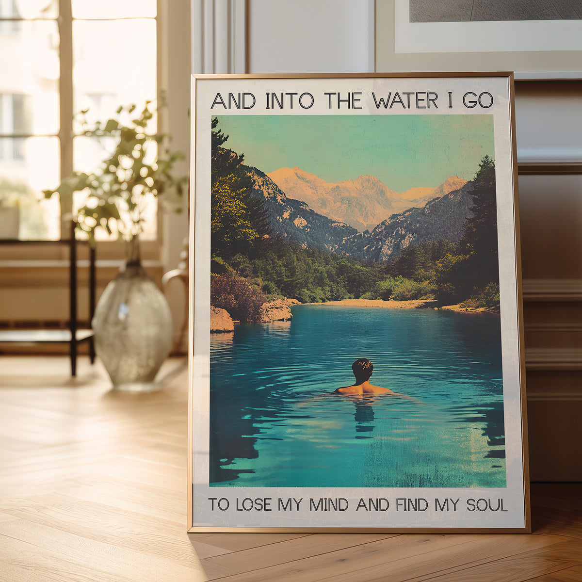 Framed poster of a person in a mountain lake with text in a room with a plant and window.